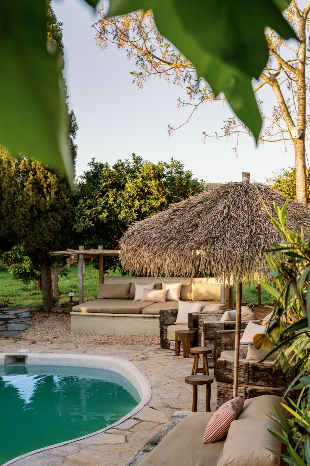 Poolside lounge with thatched parasol at Can Sastre boutique hotel, golden hour