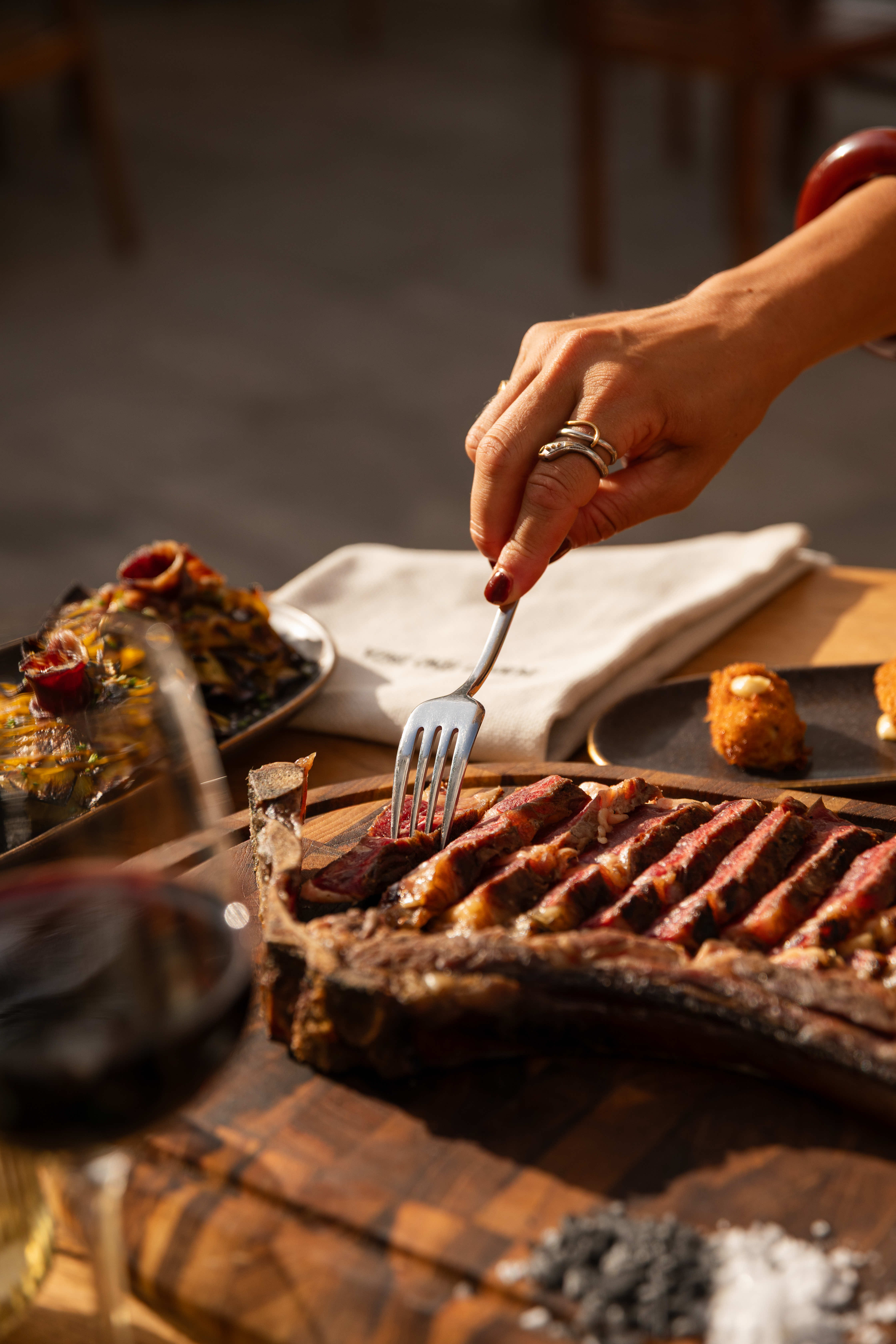Slicing into a grilled steak at Puerto Fino, golden hour on the terrace