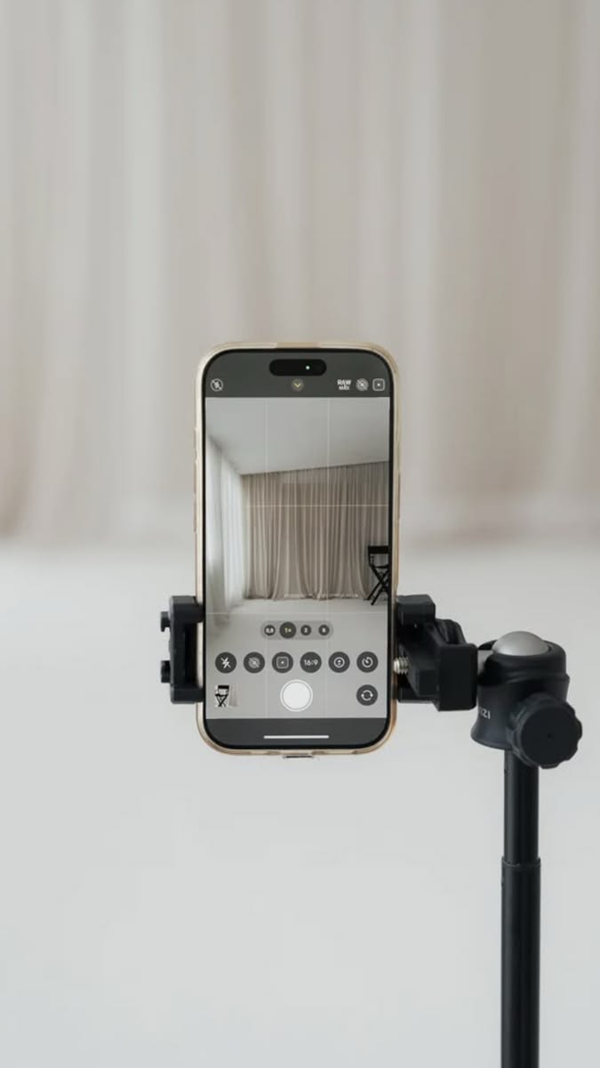 Phone mounted on a tripod, framing a shot in a curtained studio set