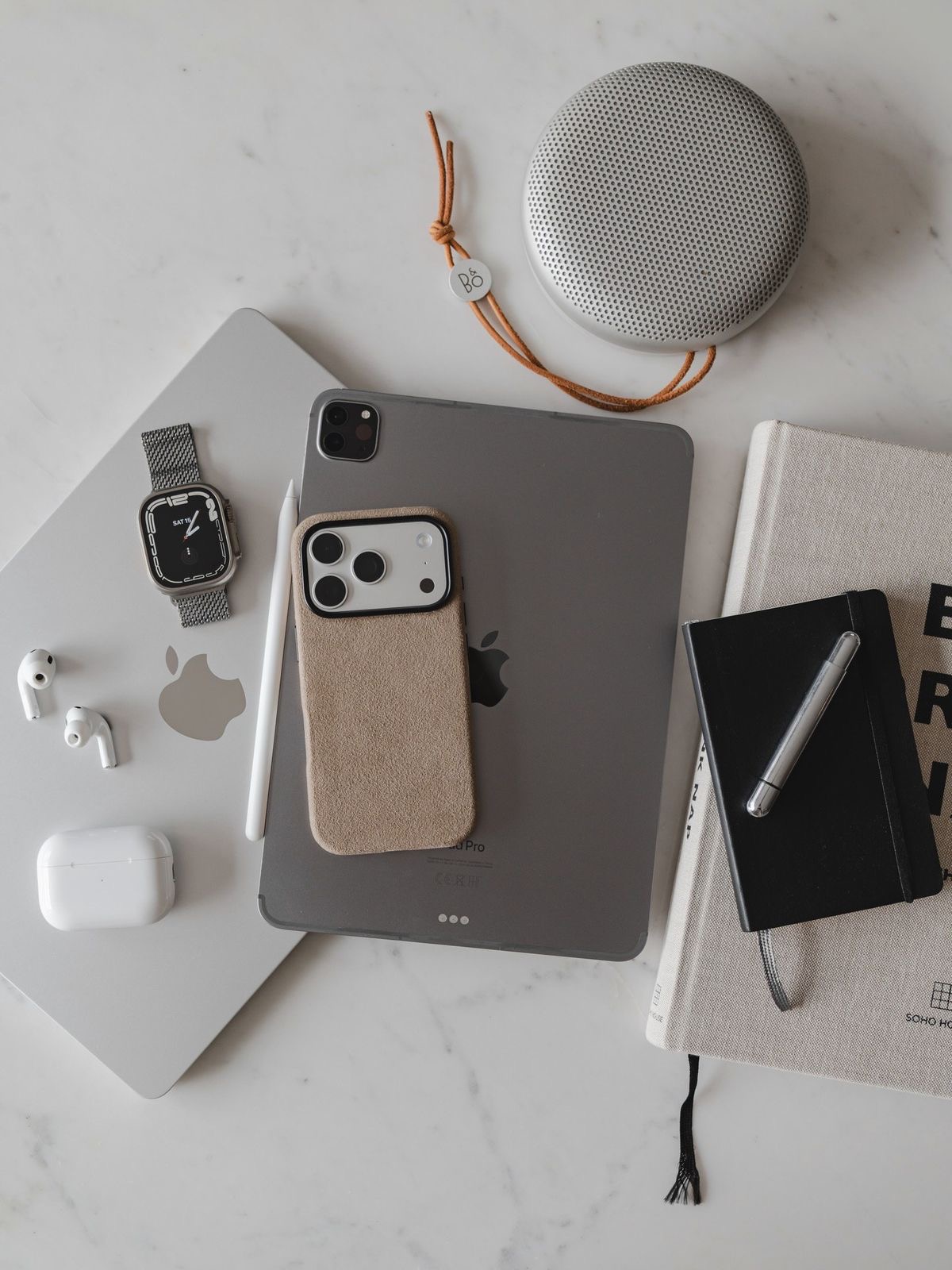 Flat lay of a phone, tablet, smartwatch and notebooks on a marble surface